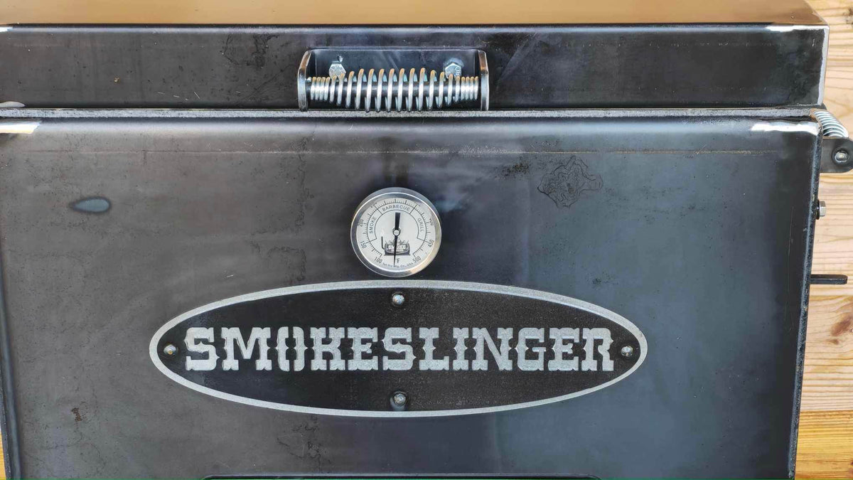 image of the front view of a smokeslinger smoker with a natural stained wood wall in the background