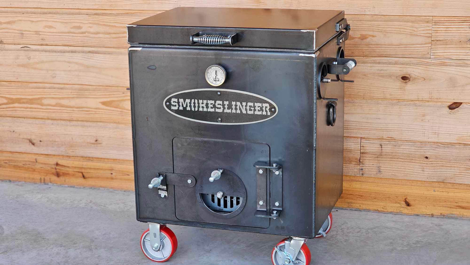 image of the top view of a smokeslinger smoker sitting on concrete with a natural stained wood wall in the bacground