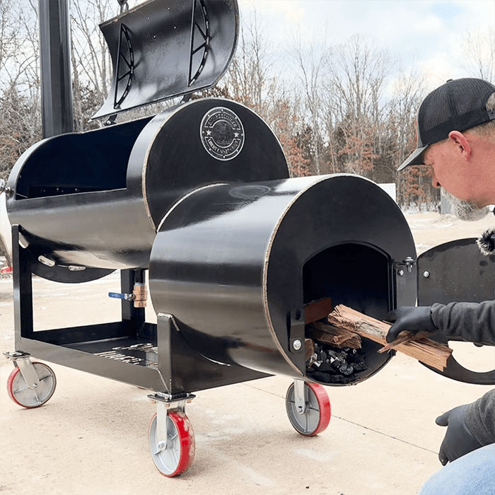 Frank Cox of smokerbuilder adding a log to the Liberty94 smoker fire box